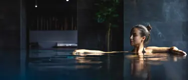 Frau entspannt mit geschlossenen Augen im Pool eines Longevity Hotels